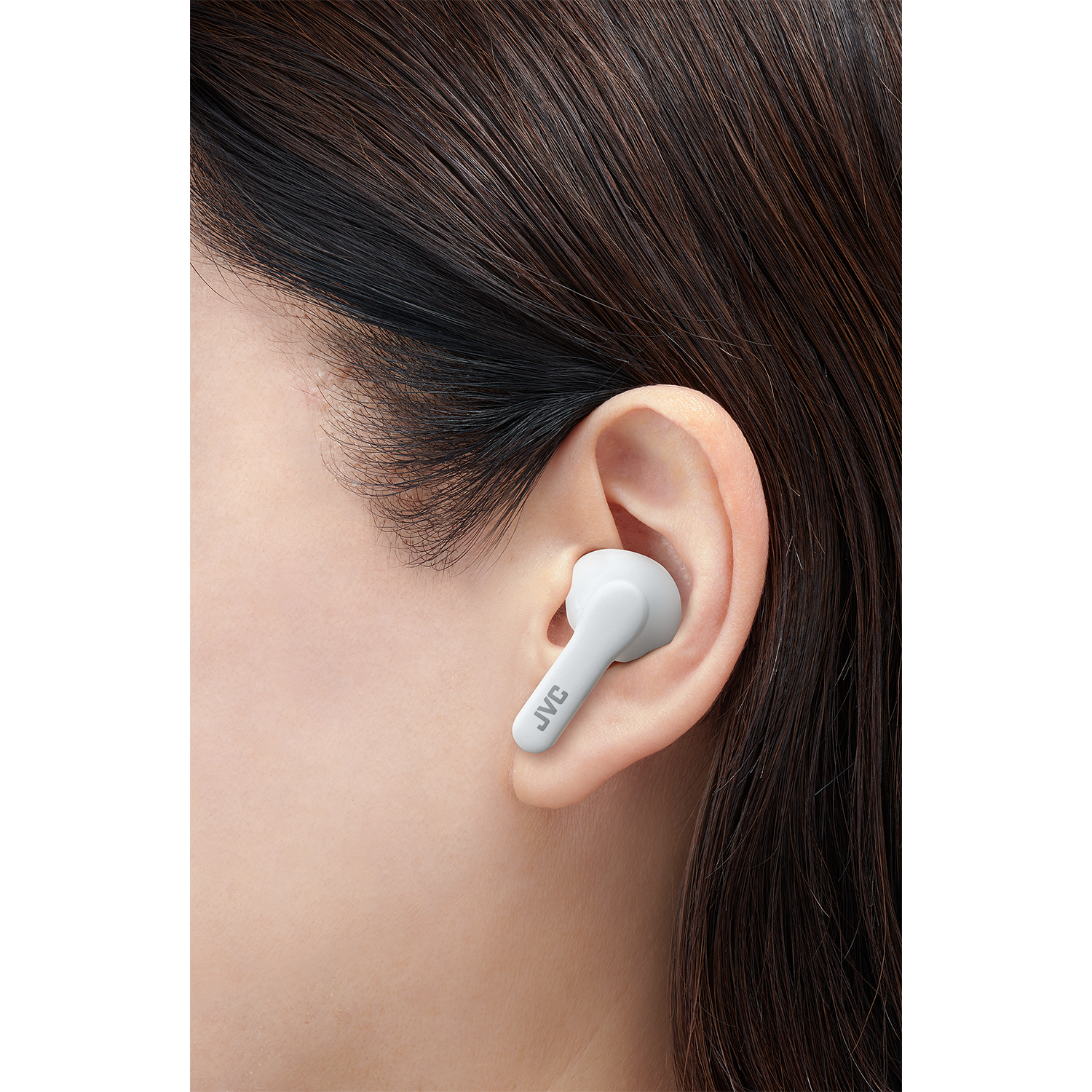 Primo piano dell'orecchio di una donna con auricolare bianco JVC inserito. L'auricolare è inserito.