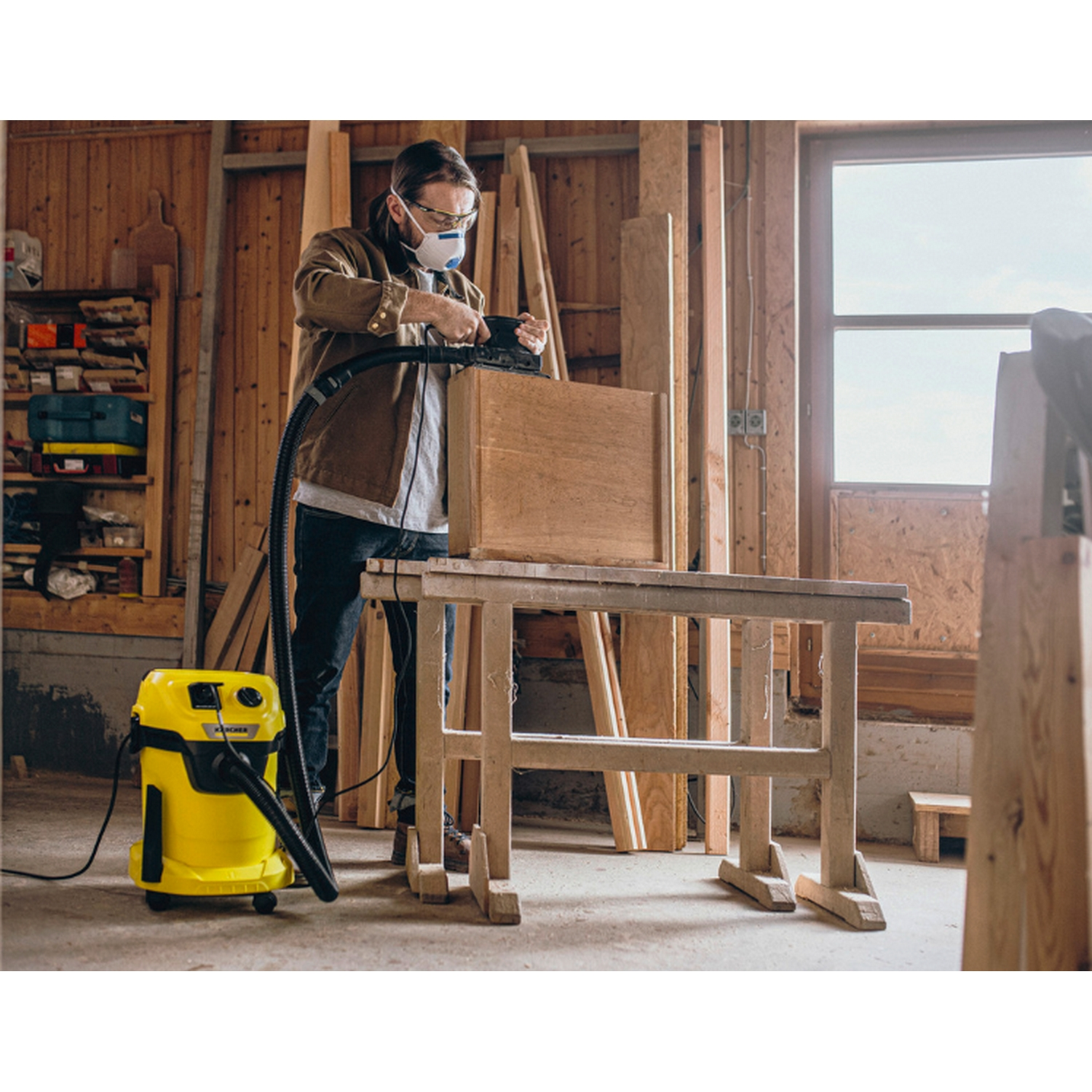 Un hombre con máscara está usando una herramienta eléctrica en una caja de madera.