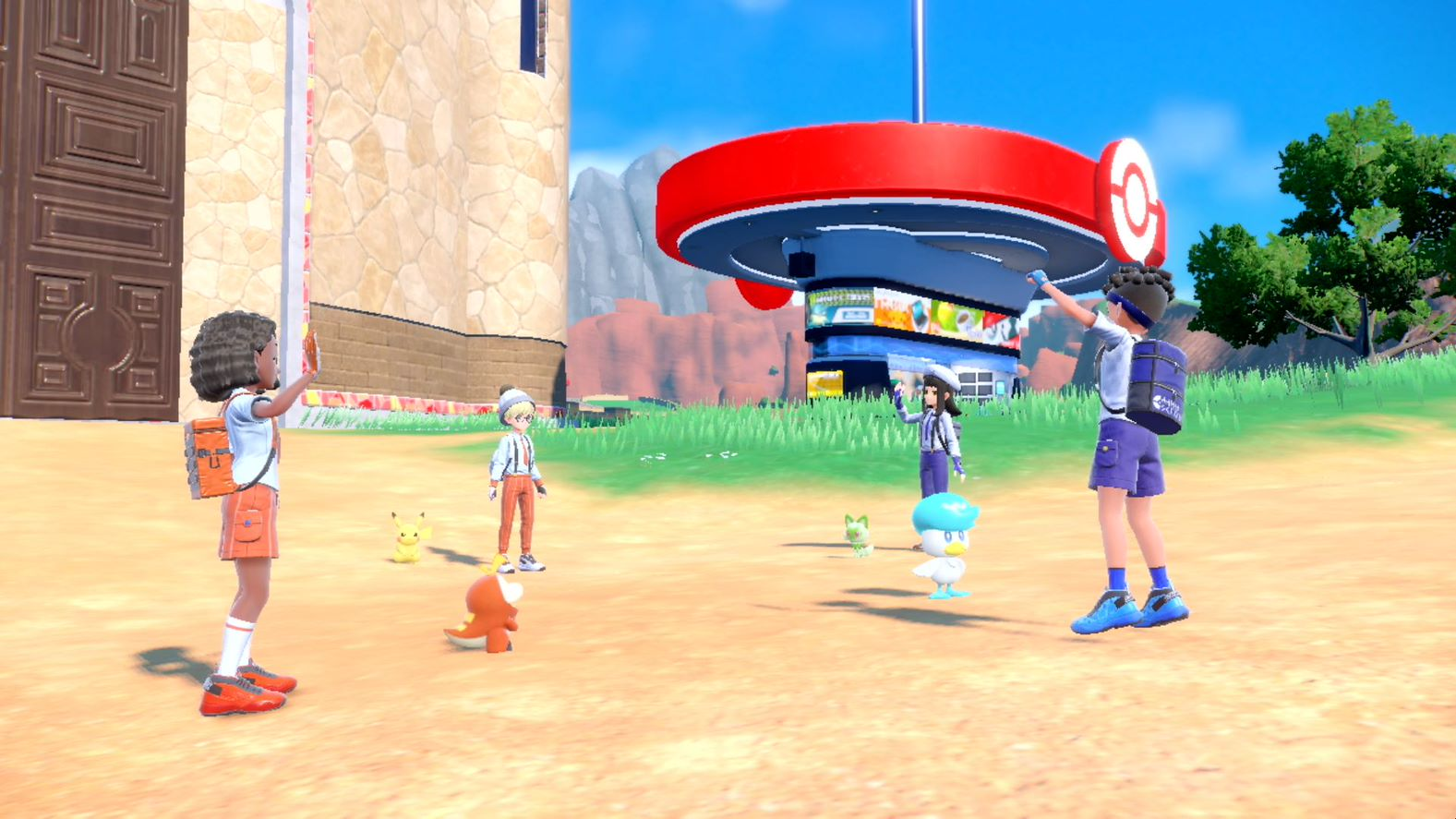 A group of people and Pokémon characters near a building in a sunny outdoor scene.