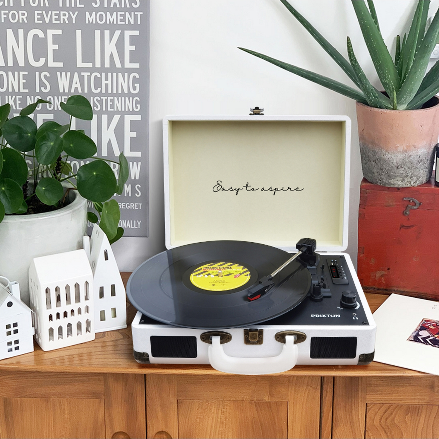 Tocadiscos reproduciendo un disco de vinilo. Tocadiscos blanco, otros objetos en madera.