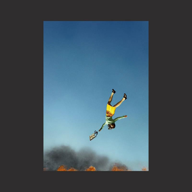 Eine Person fällt vom Himmel, umgeben von Feuer und Rauch.