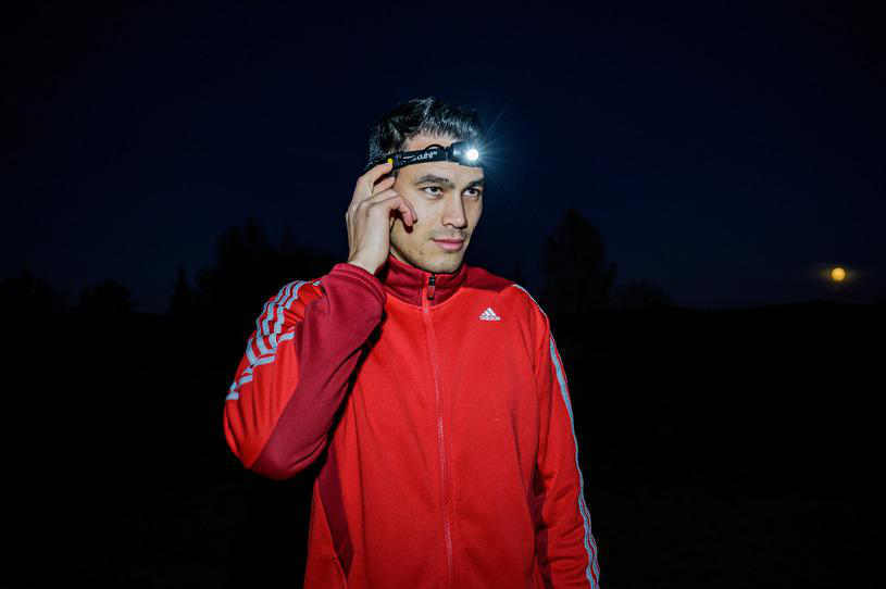 Mann mit Stirnlampe bei Nacht, roter Jacke und Vollmond.