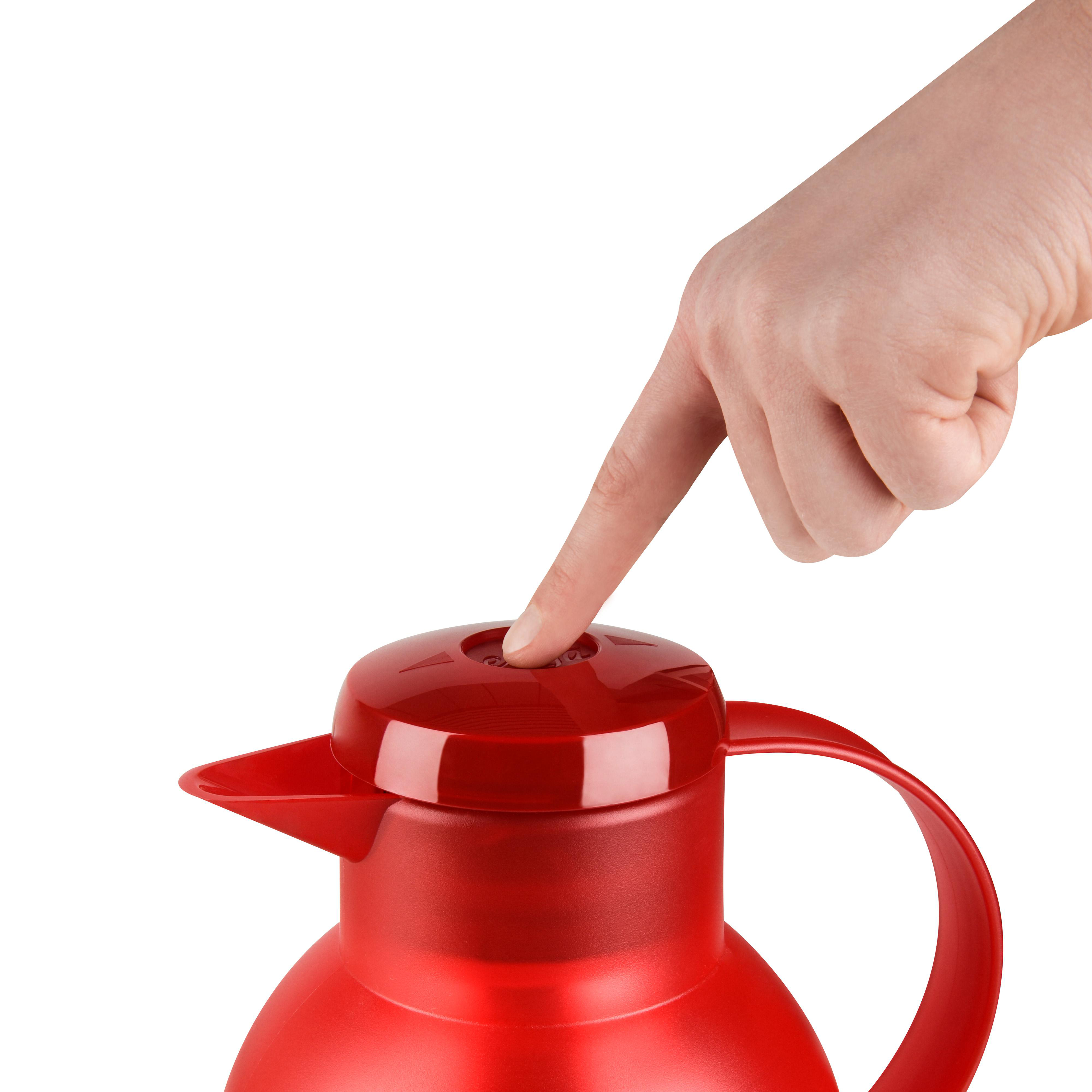 Eine Hand drückt eine rote Taste auf einer roten Thermoskanne mit Griff und Ausguss.