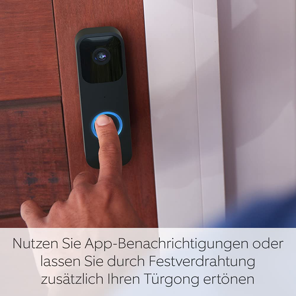 Eine Hand drückt eine Türklingel mit blauem Lichtring, eine schwarze Türklingel an einer Holztür.