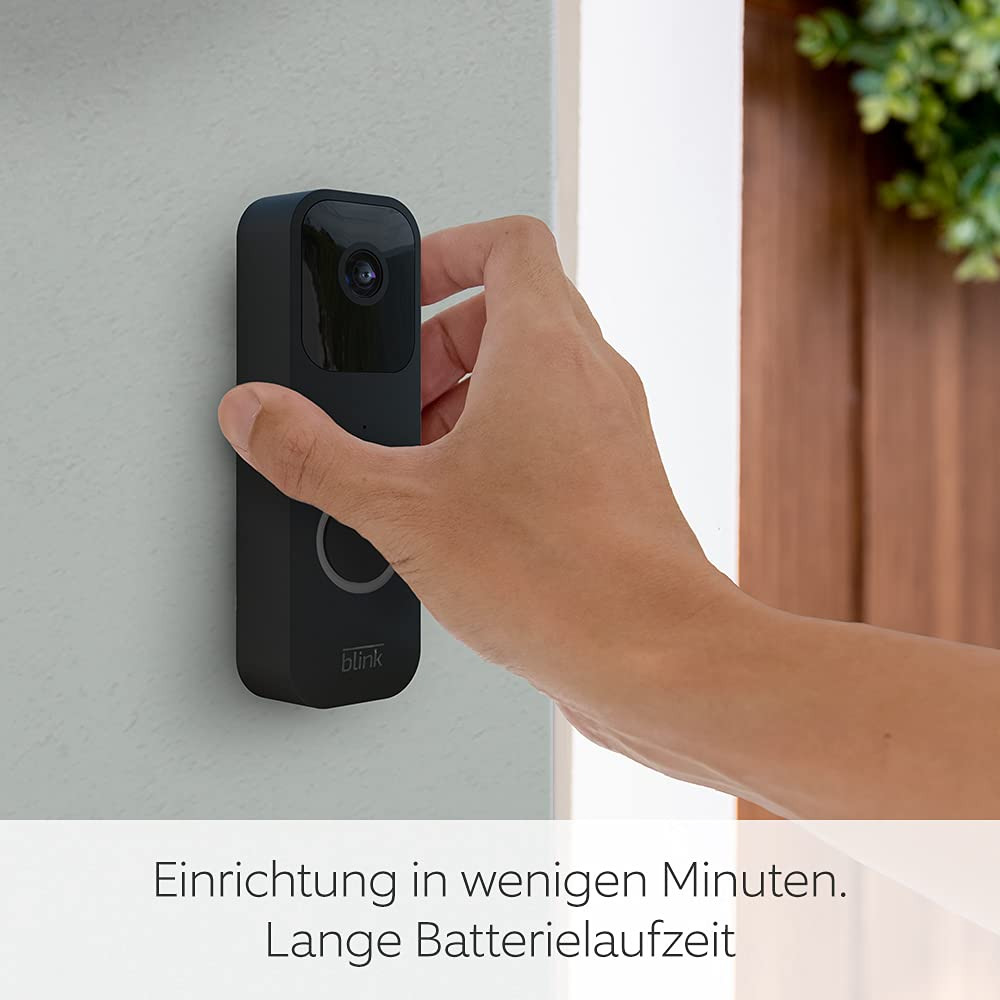Person installiert eine schwarze intelligente Türklingel an einer weißen Wand.