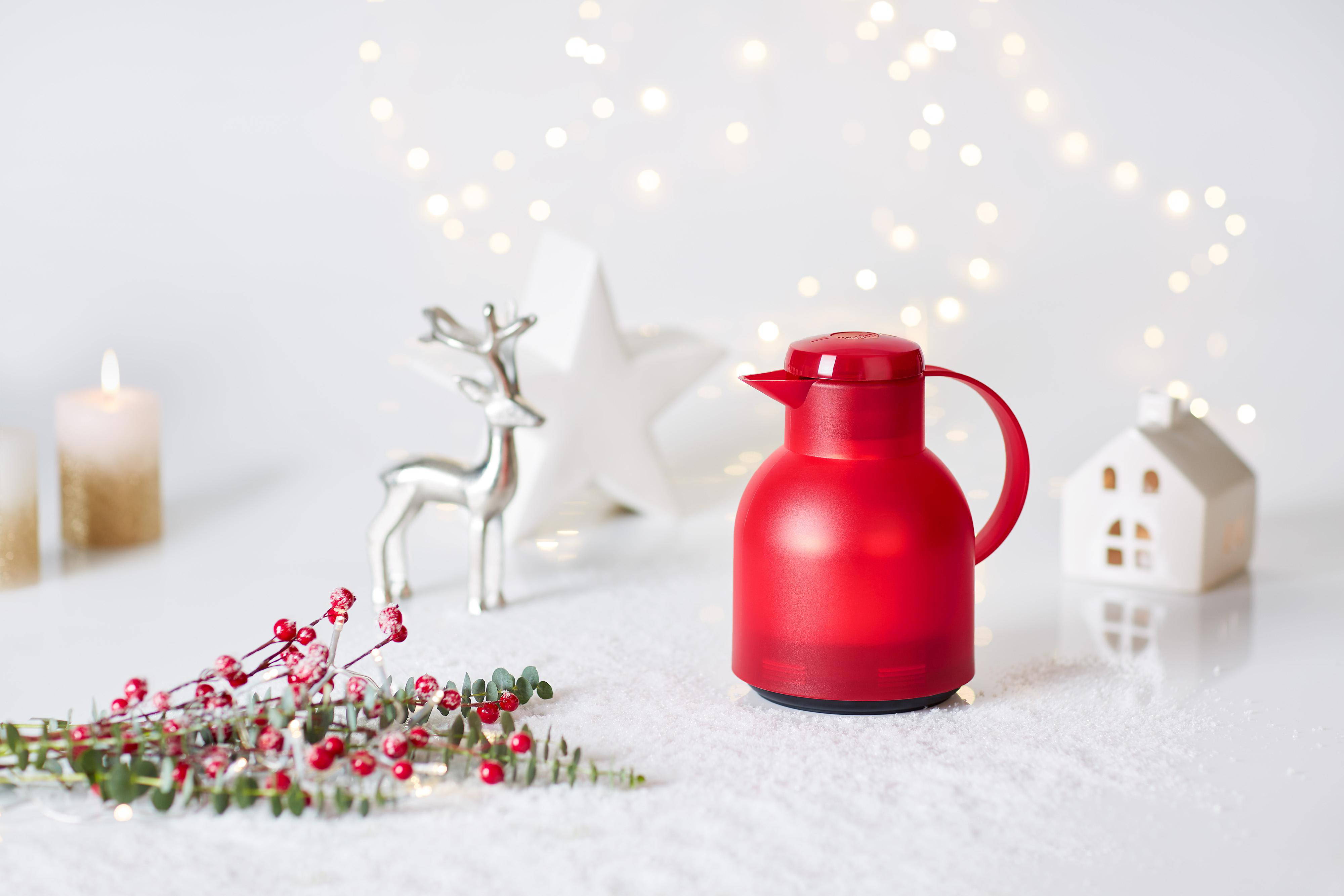 Rote Thermoskanne. Weihnachtsszene mit Dekorationen und Lichtern.