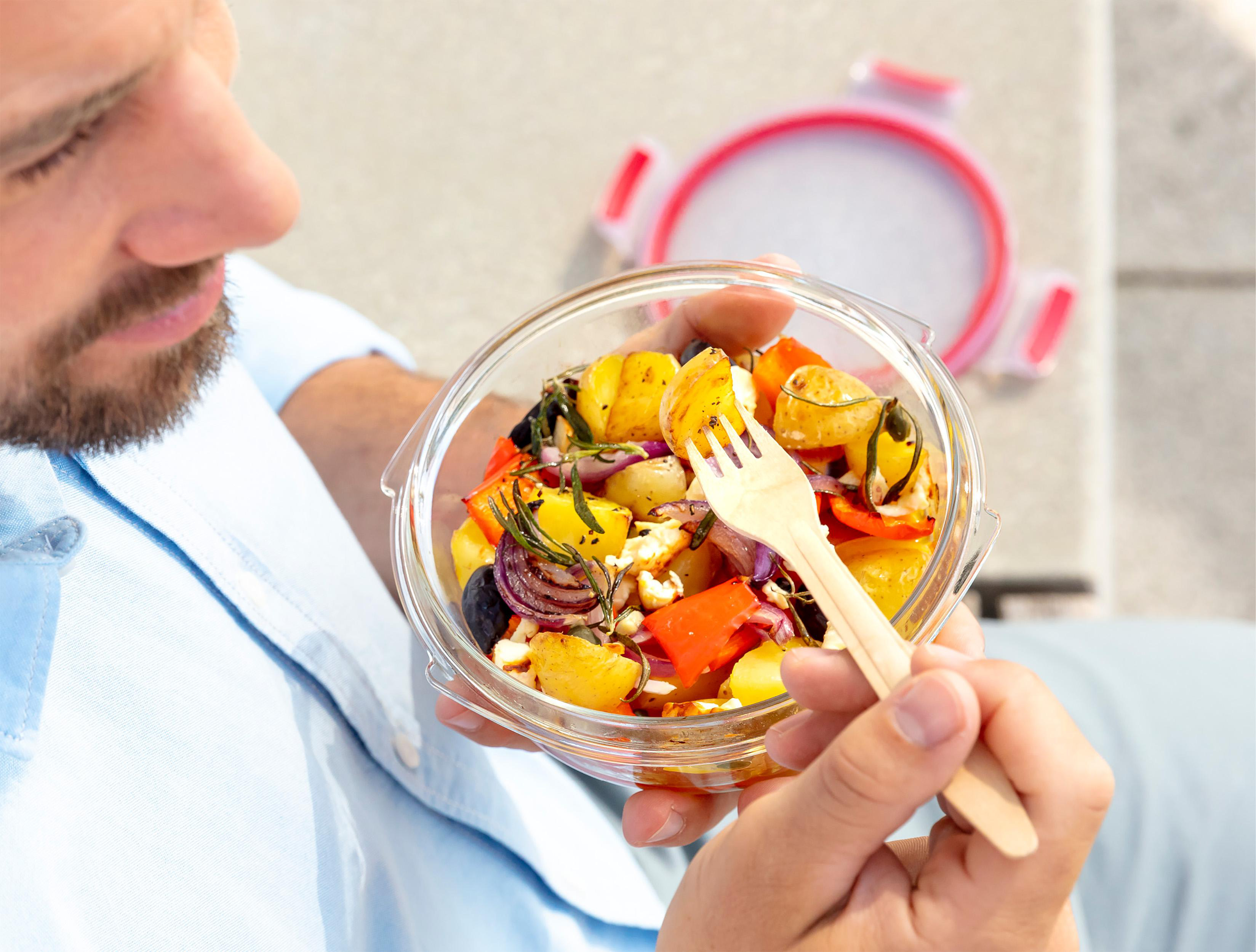 Ein Mann, der mit einer Gabel Salat aus einer Schüssel isst.