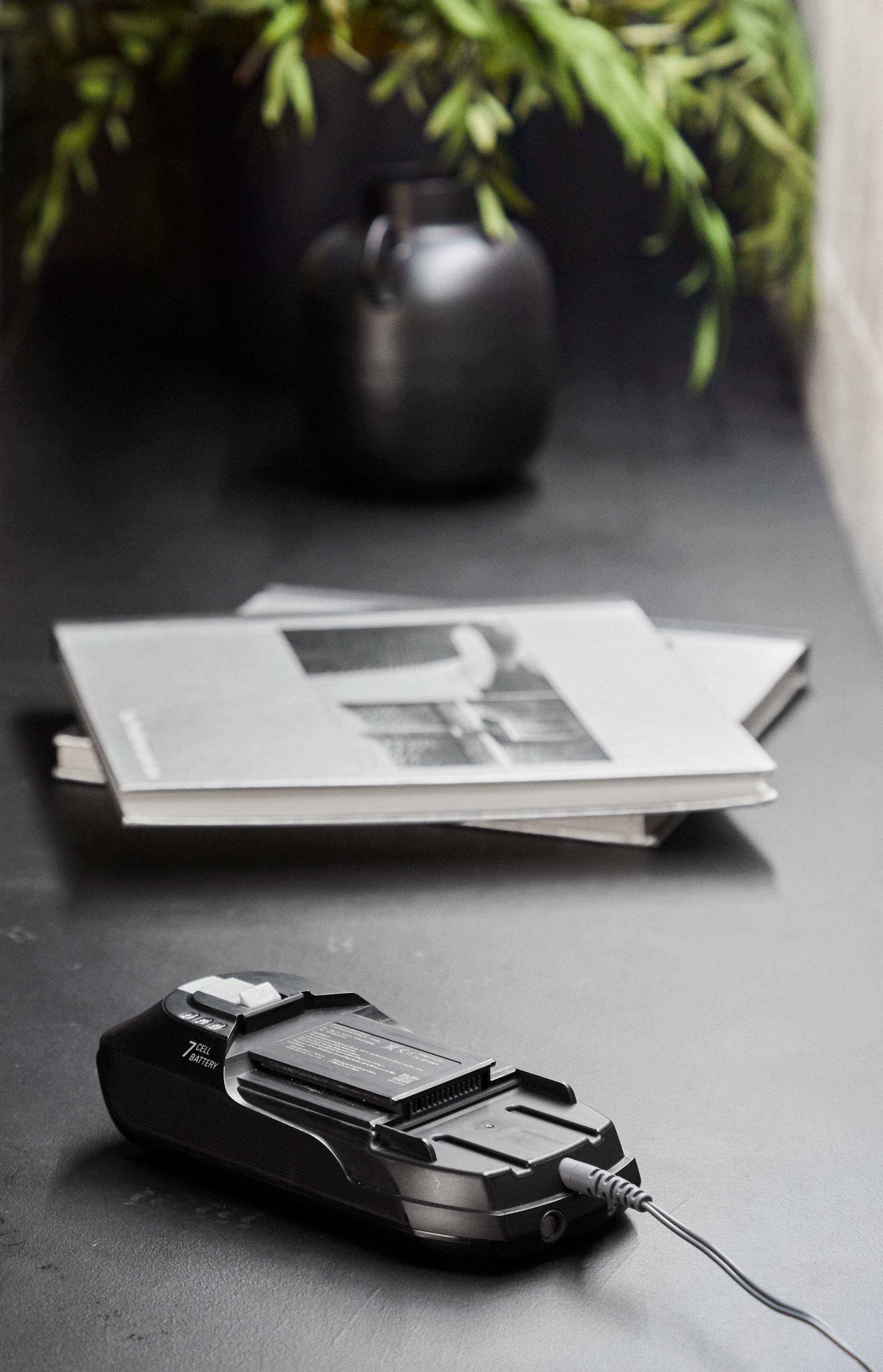 Schwarzes Ladegerät mit Akku, Büchern und einer schwarzen Vase.