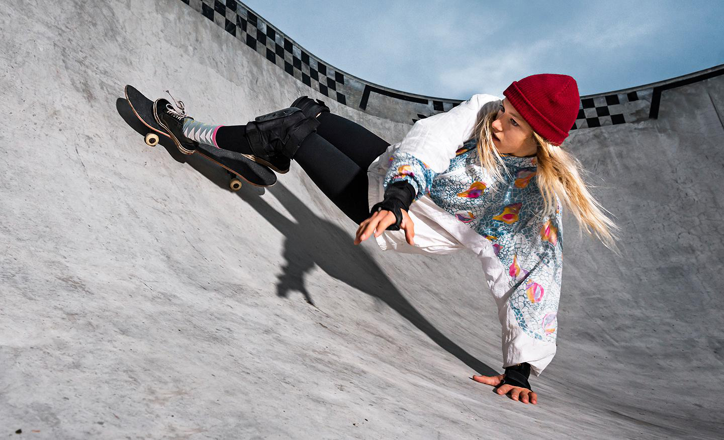 Frau auf Skateboard in Skatepark, an der Rampe lehnend.