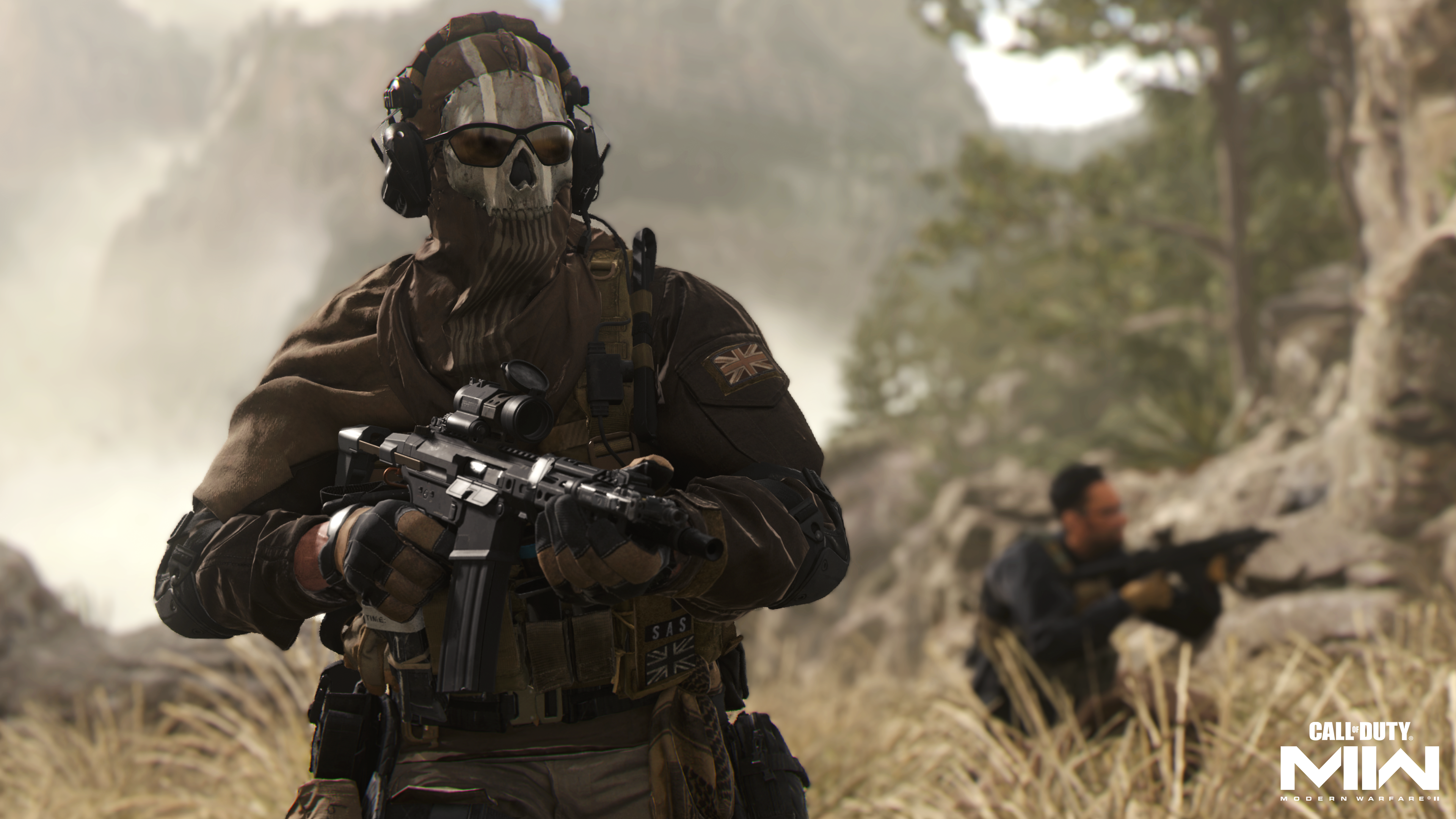 Ein Soldat in Totenkopfmaske und taktischer Ausrüstung mit Gewehr in einer Graslandschaft mit einem weiteren Soldaten.