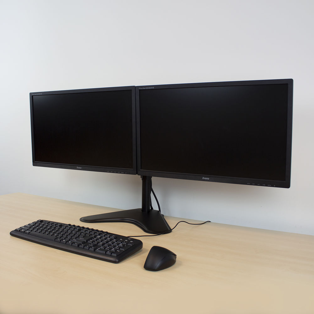Two computer monitors on a desk with a keyboard and mouse. White wall in the background.