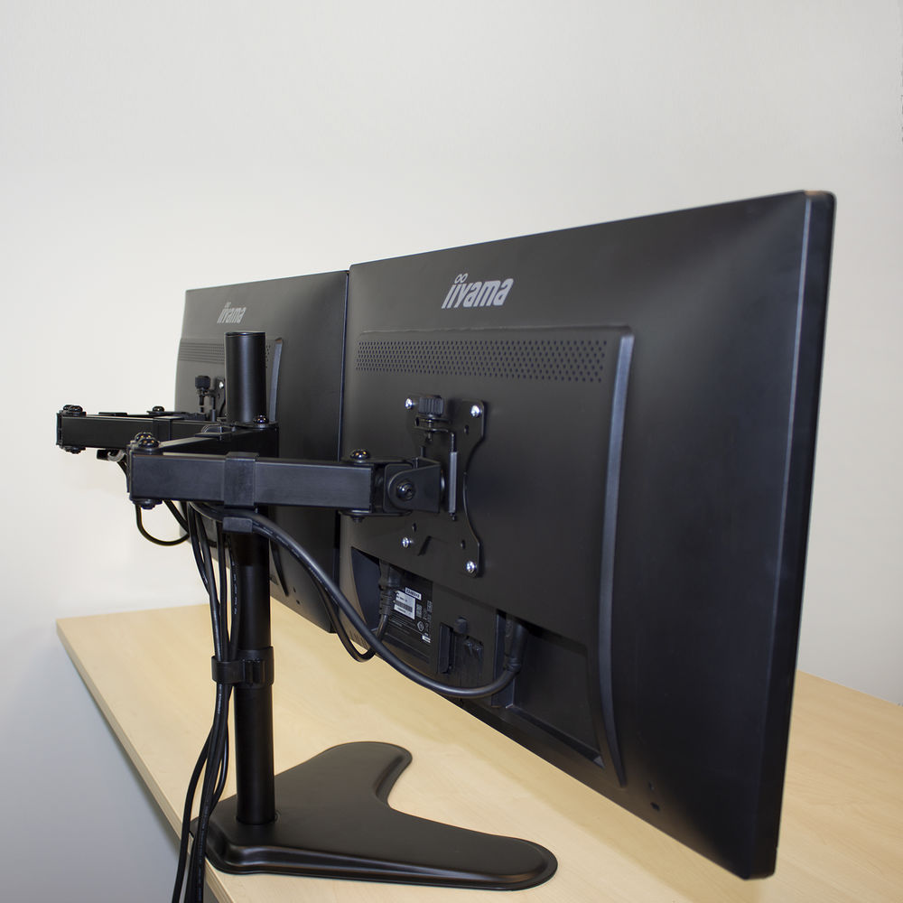 Two black computer monitors mounted on a desk with an arm support.
