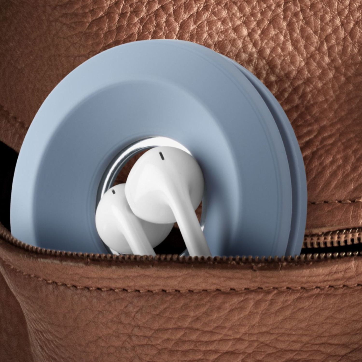 Earbuds in a light blue holder inside a brown pocket. The pocket has a zipper.
