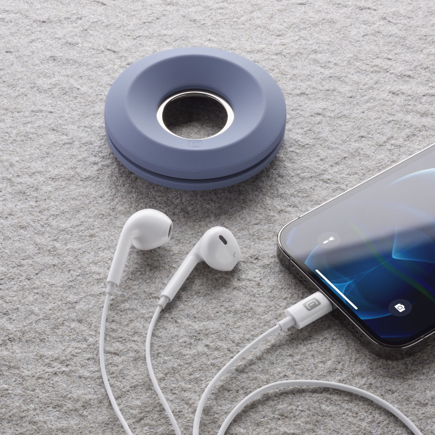 Earphones connected to a phone. A blue round cable organizer is on the top left.
