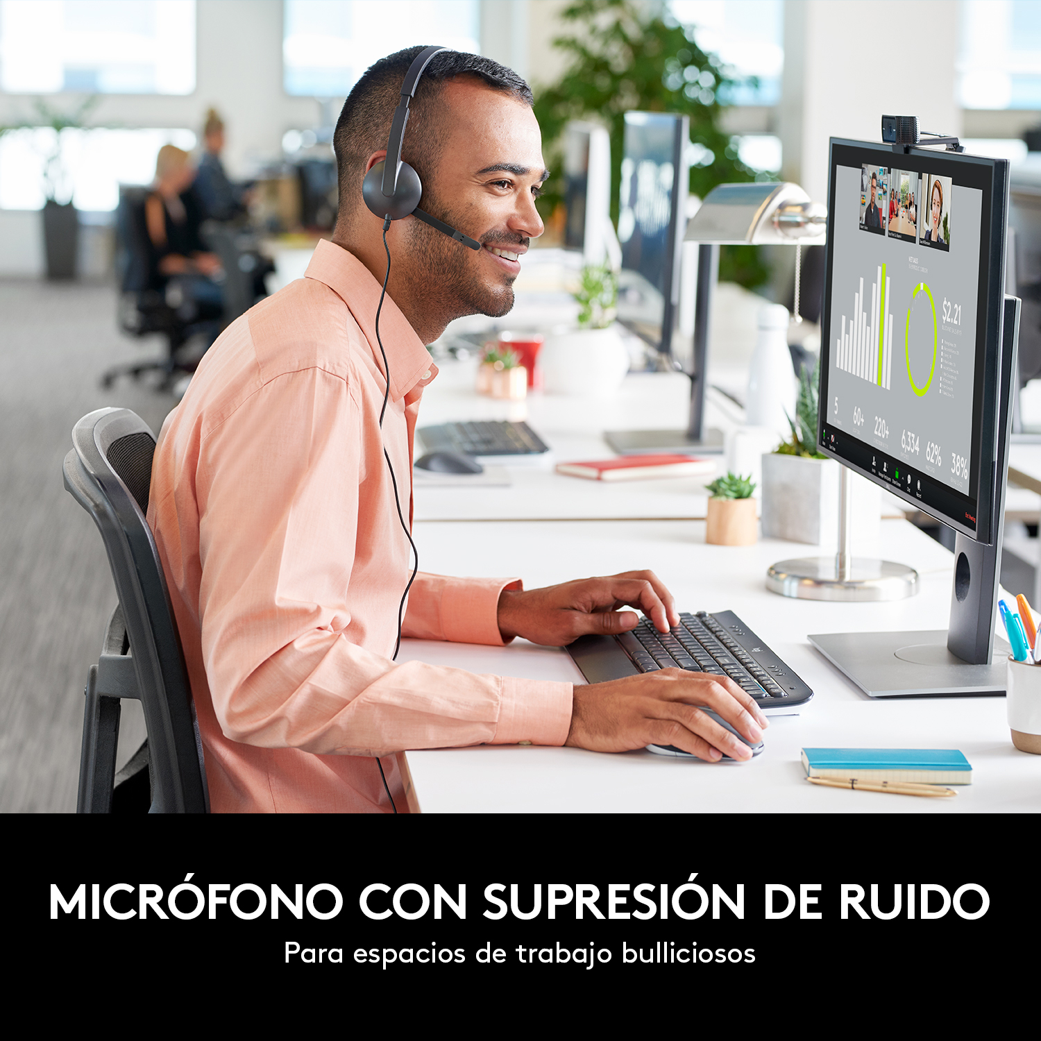 Hombre con auriculares, sonriendo, trabajando en un escritorio. Pantalla con videollamada y gráficos.