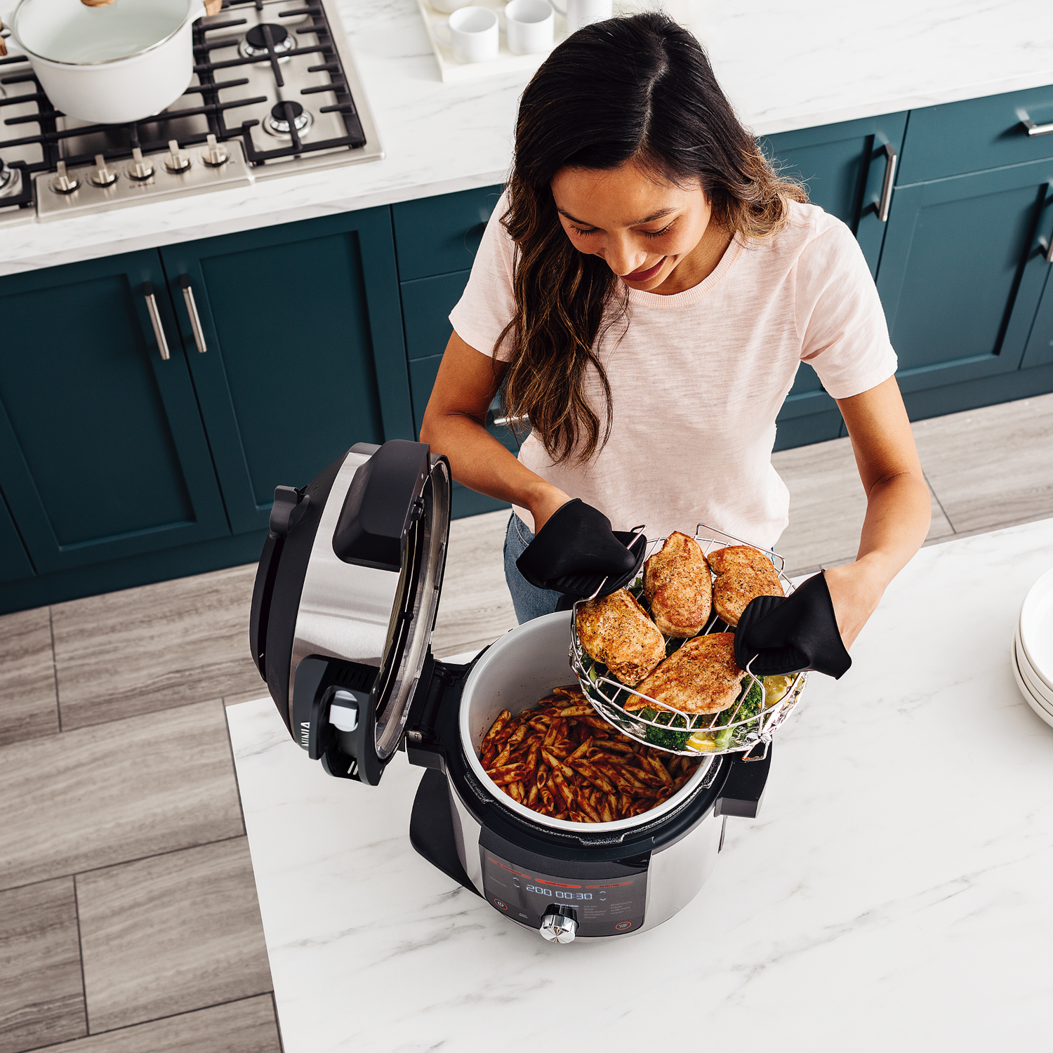 Een vrouw met een Ninja Foodi die in de keuken kookt.