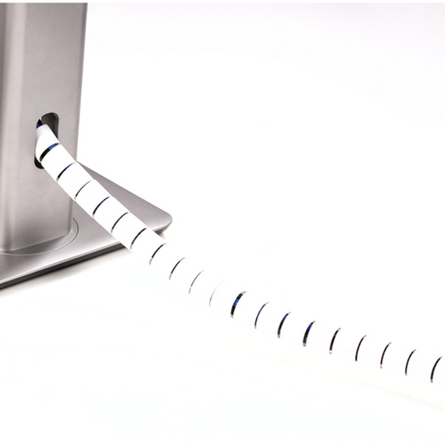 Organizador de cable blanco con diseño en espiral. Se curva y sale de un soporte plateado.