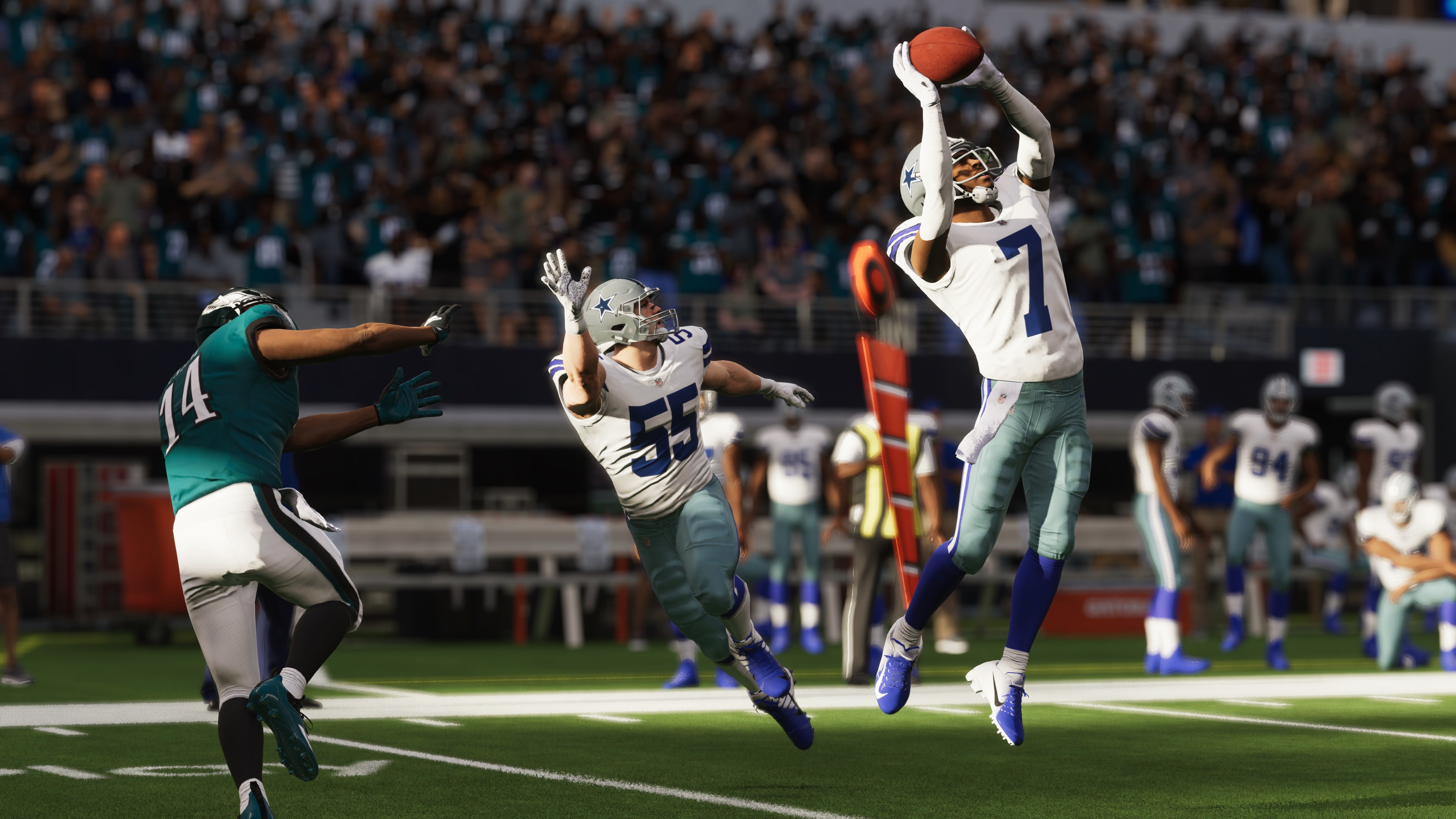 Footballspiel-Action, ein Spieler der Dallas Cowboys fängt einen Pass in der Luft.