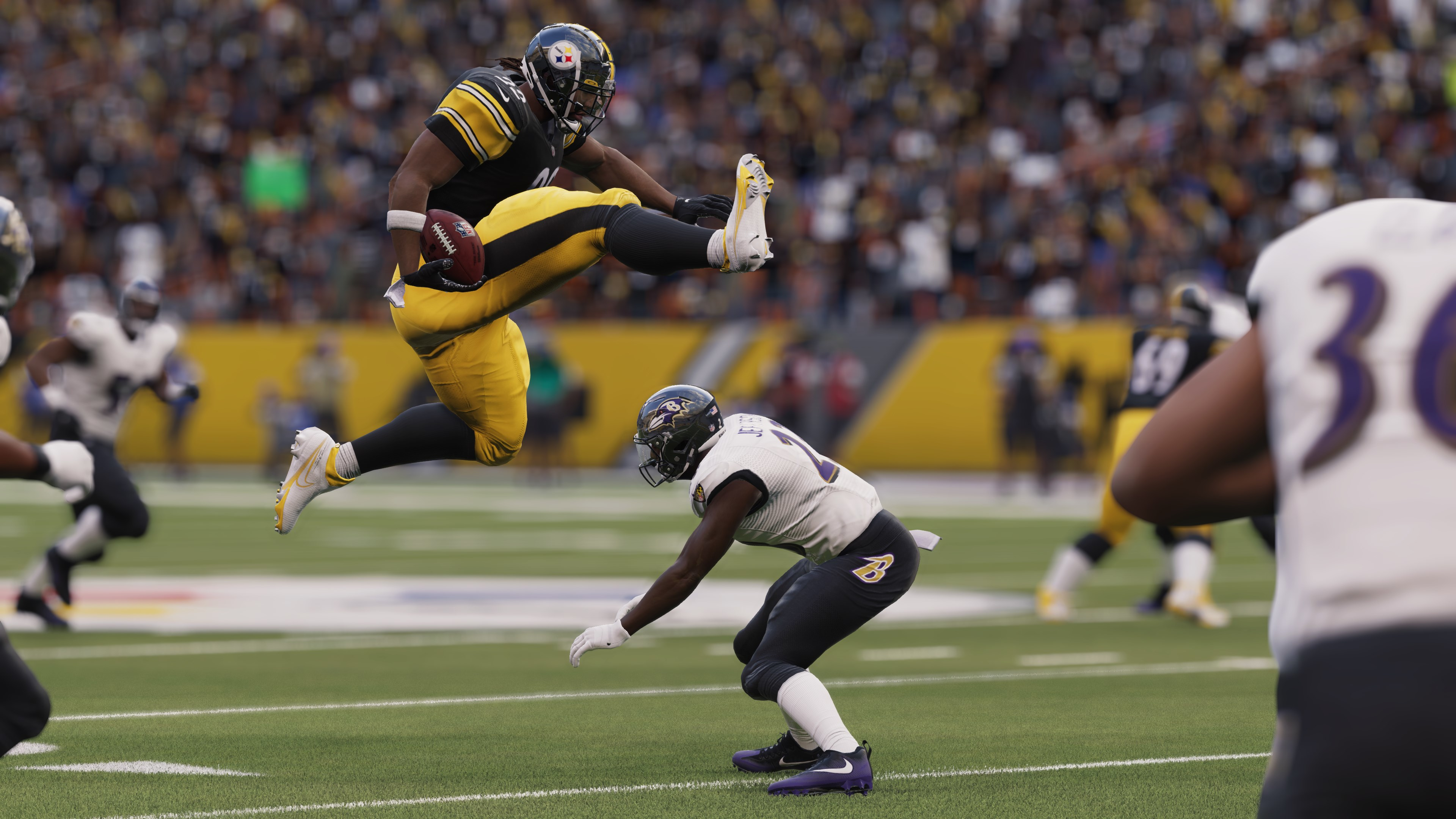 Footballspieler in Aktion. Ein Steelers-Spieler springt über einen Raven-Spieler. Der Ball ist in der Hand.
