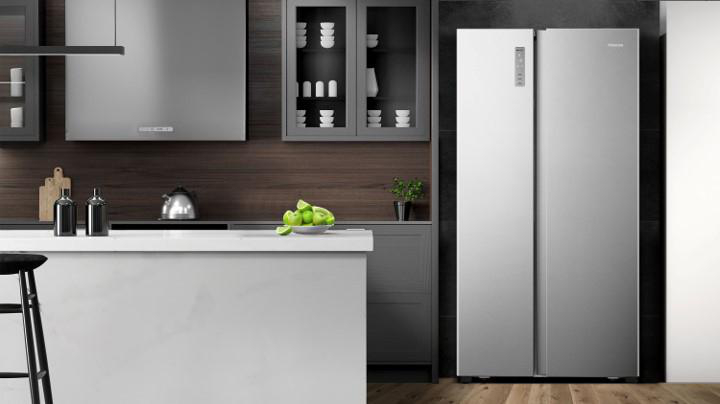 Eine moderne Küche mit einem Edelstahlkühlschrank, einer weißen Insel und einem schwarzen Barhocker.