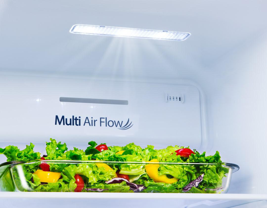 Eine Glasschüssel mit Salat im Inneren eines Kühlschranks.