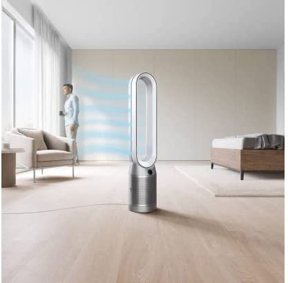 Purificador de aire moderno en una habitación con un hombre mirando afuera, una cama y una silla.