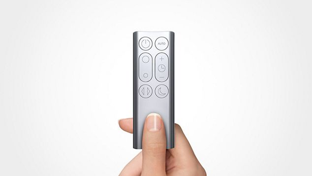 Un mando a distancia Dyson plateado sostenido por una mano. Tiene varios botones.