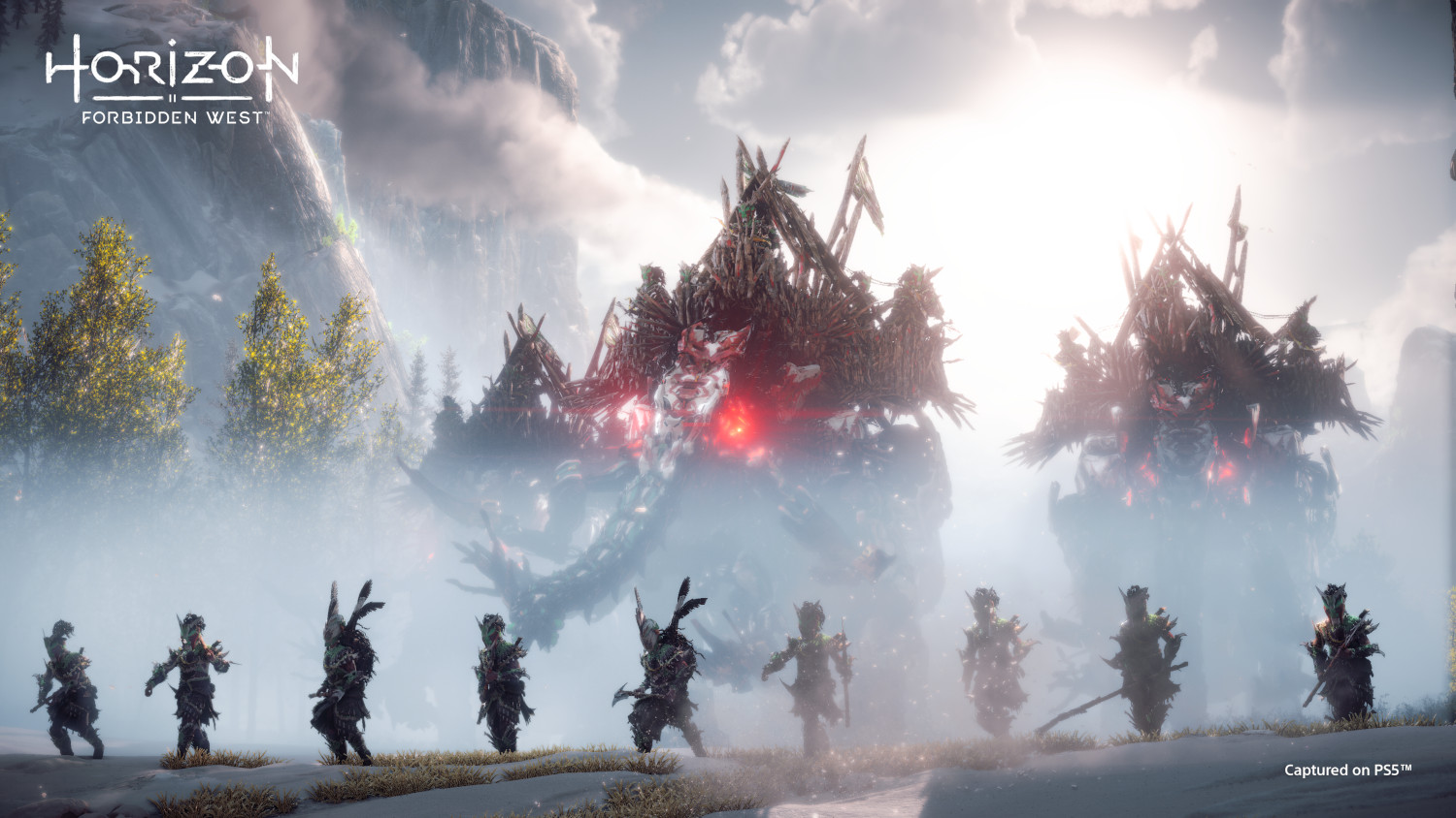 Warriors in armor stand before massive, ominous machines under a hazy sky.