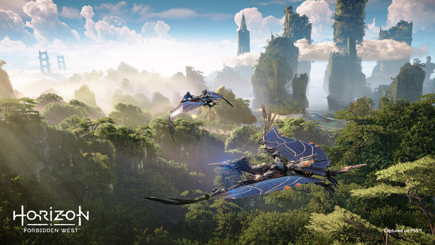 Two winged machines fly over lush green forests and rugged mountains.