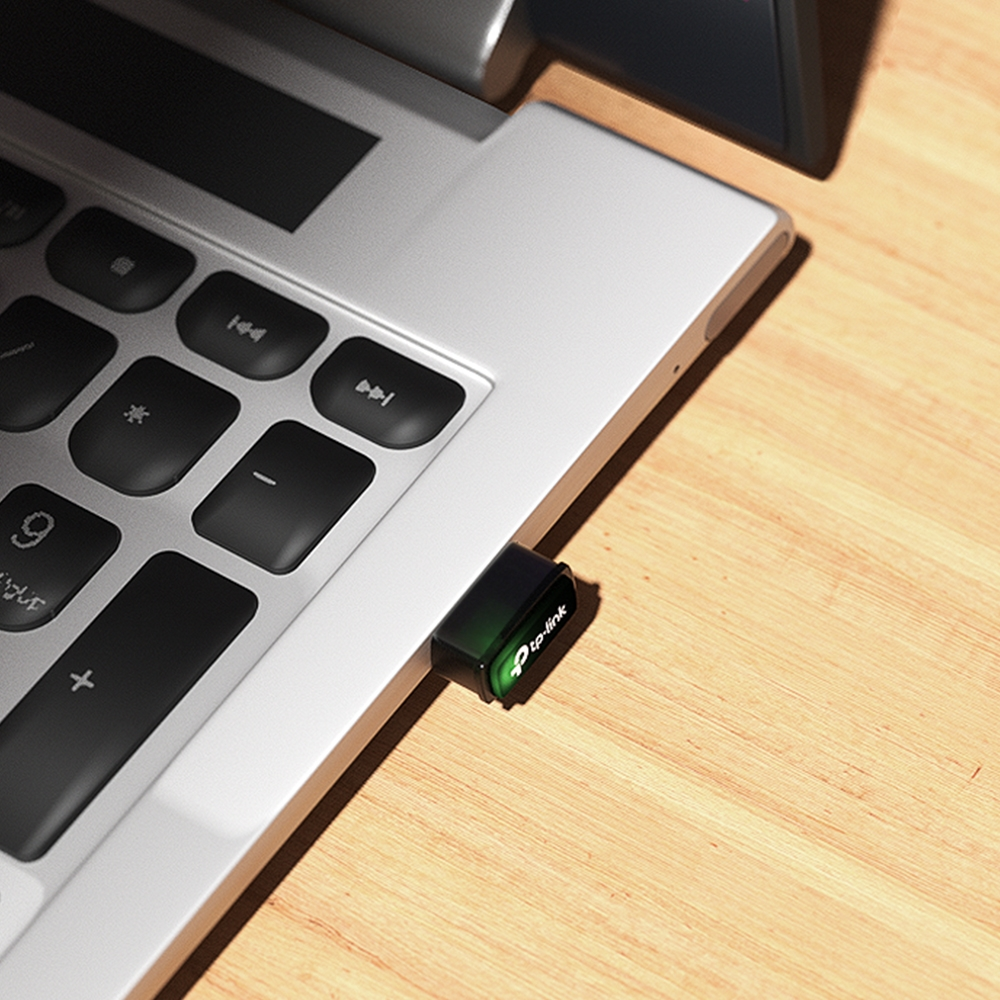 Un adaptateur USB-C branché sur un ordinateur portable, sur une surface en bois, corps vert et logo blanc.