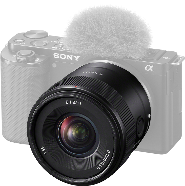 Un objectif d'appareil photo noir avec un microphone blanc sur le dessus. L'appareil photo est partiellement visible en arrière-plan.
