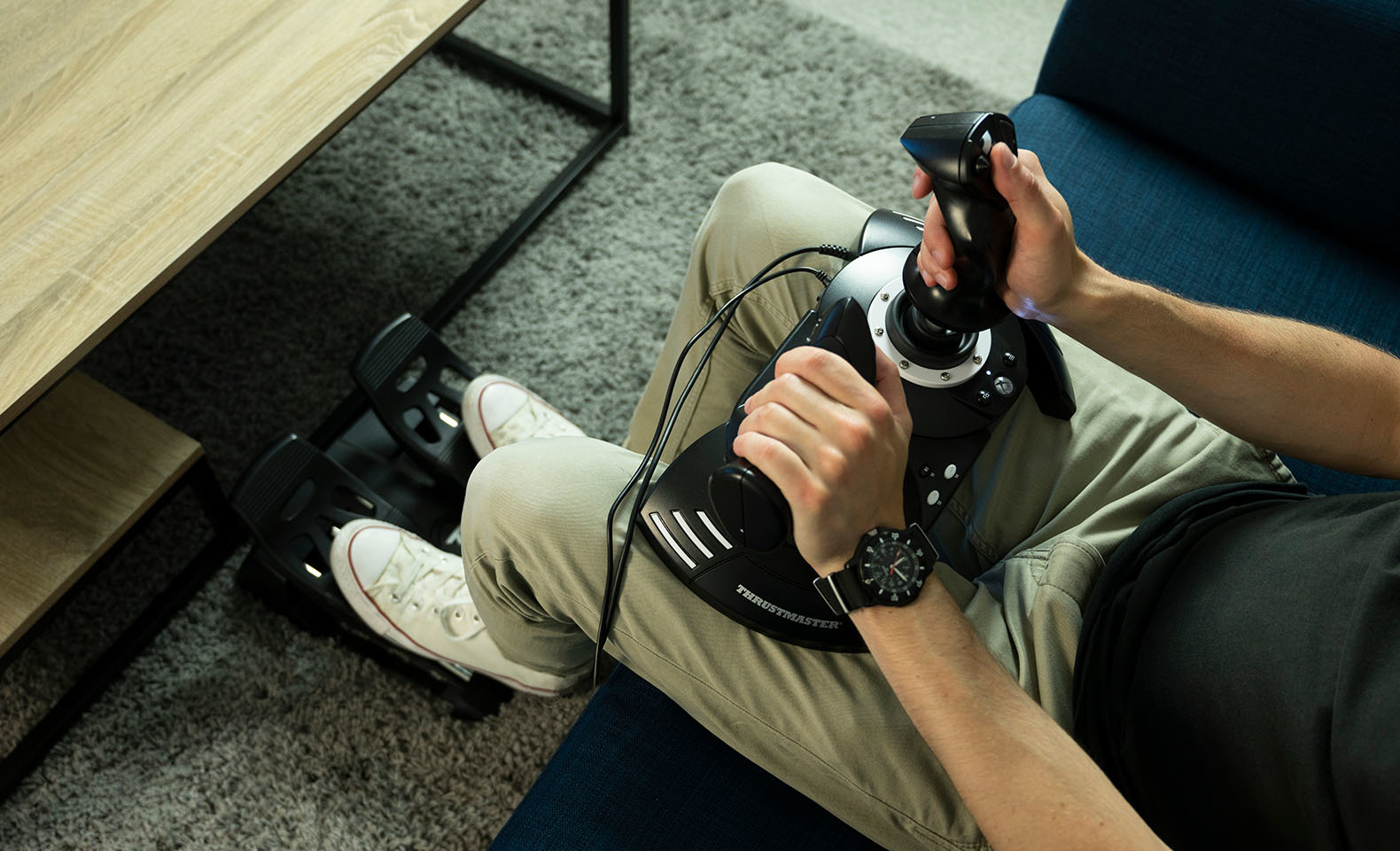 Persona seduta con joystick e pedali, vista dall'alto.
