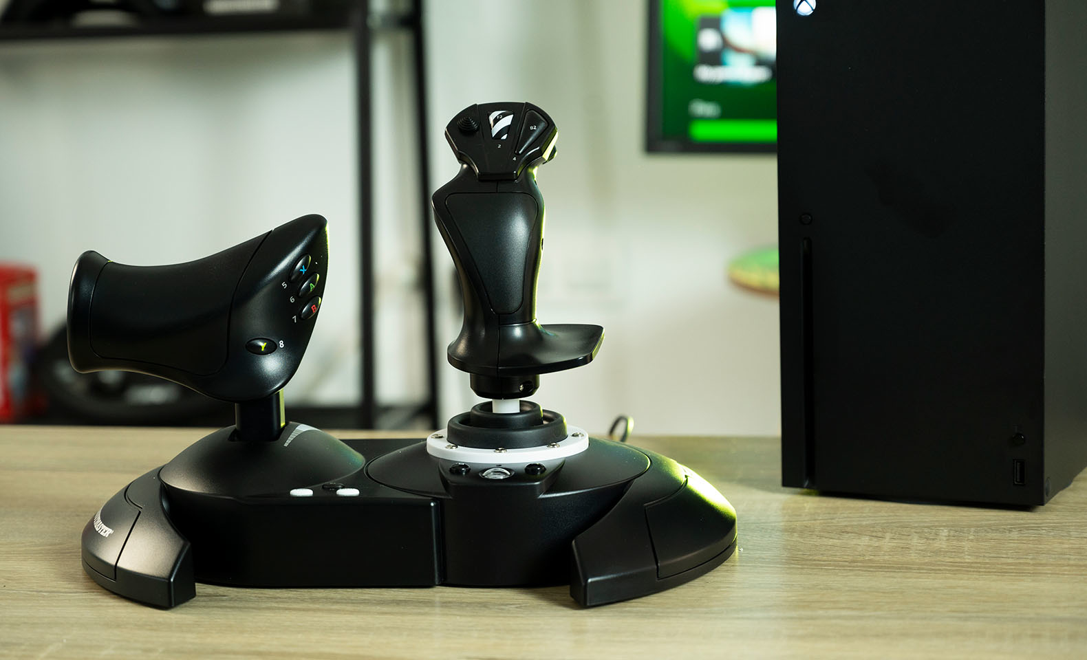 Controller di gioco joystick e acceleratore neri con console nera su tavolo.