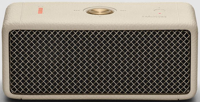 Beige luidspreker met een mesh voorkant en een gouden bedieningsknop. Rood licht zichtbaar.