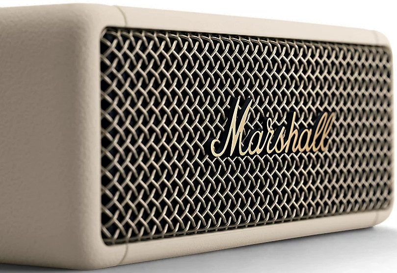 Een beige Marshall-luidspreker met een goudkleurig gaasfront en het Marshall-logo, op een witte achtergrond.
