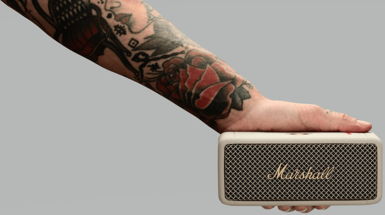 Een getatoeëerde arm die een witte Marshall-luidspreker vasthoudt.