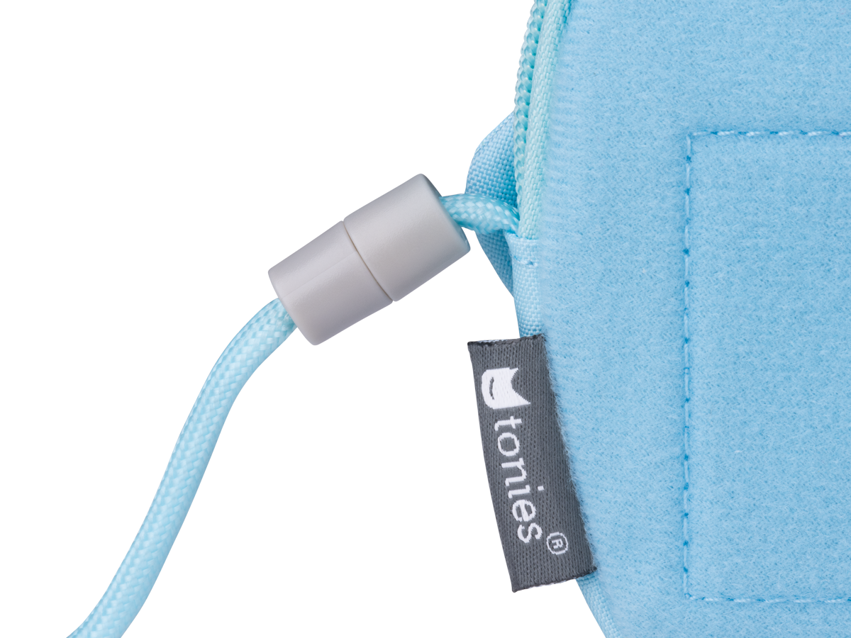 Eine hellblaue Toniebox-Tasche mit weißem Kordel und grauem Stopper, auf schwarzem Hintergrund.