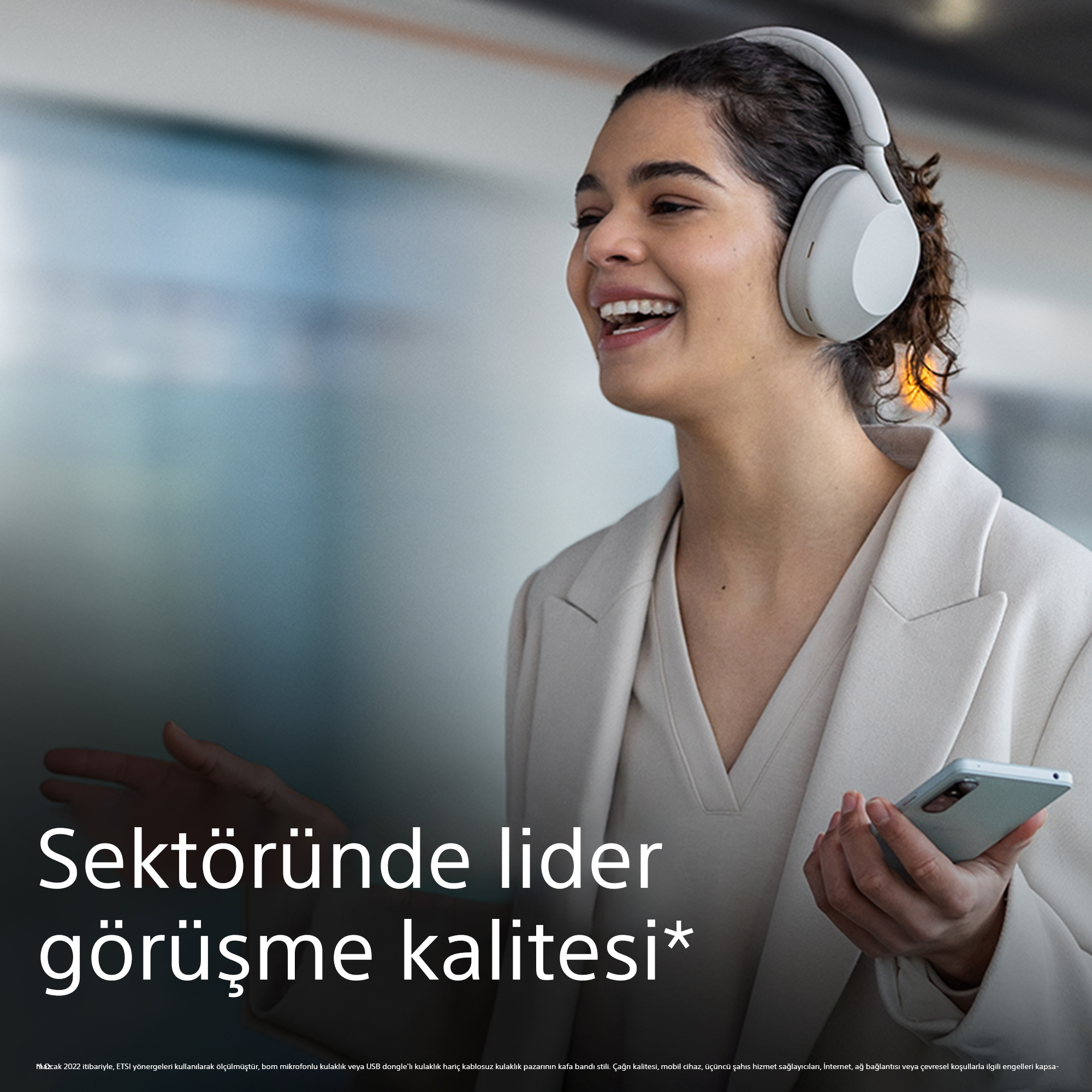 Beyaz kulaklık takan ve telefon tutan gülümseyen bir kadın. Türkçe metin: 'Sektöründe lider görüşme kalitesi'.