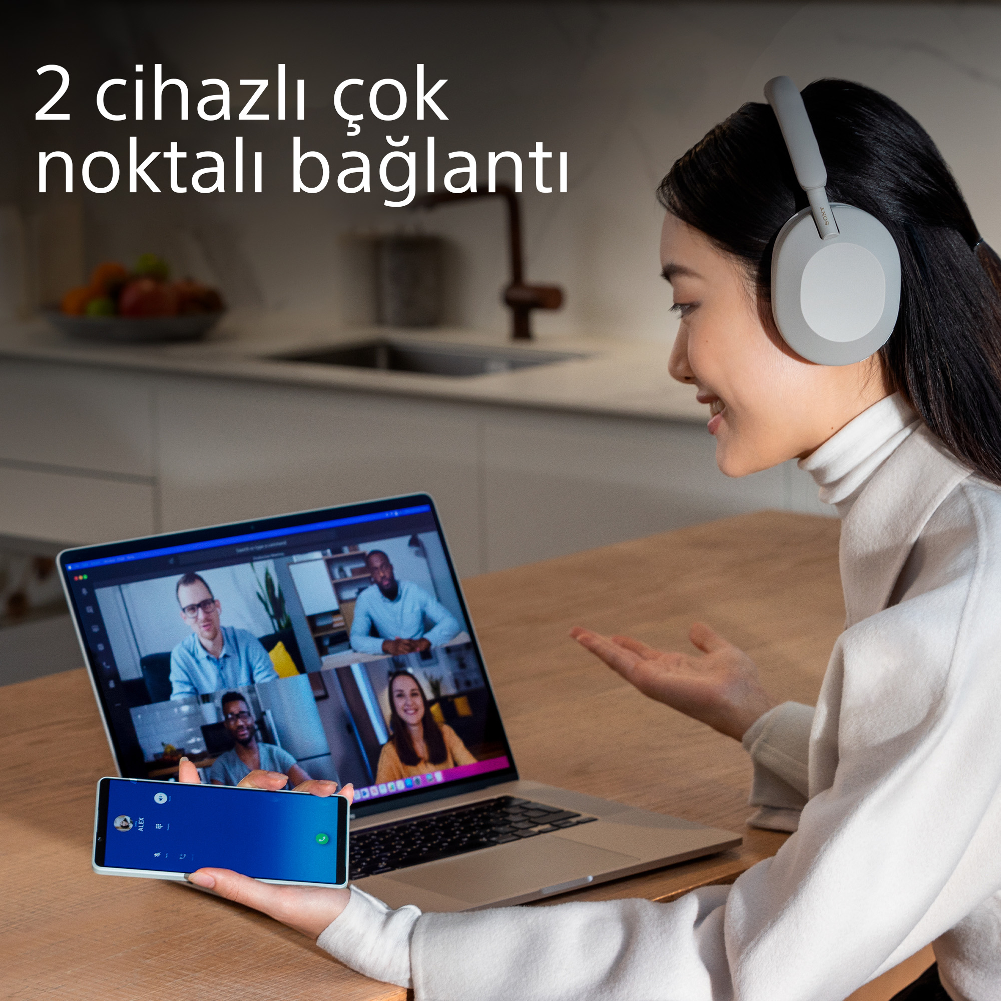 Dizüstü bilgisayar ve telefonda görüşme yapan kadın. Metin: 2 cihazlı çok noktalı bağlantı. Kadının bir kulaklığı var.
