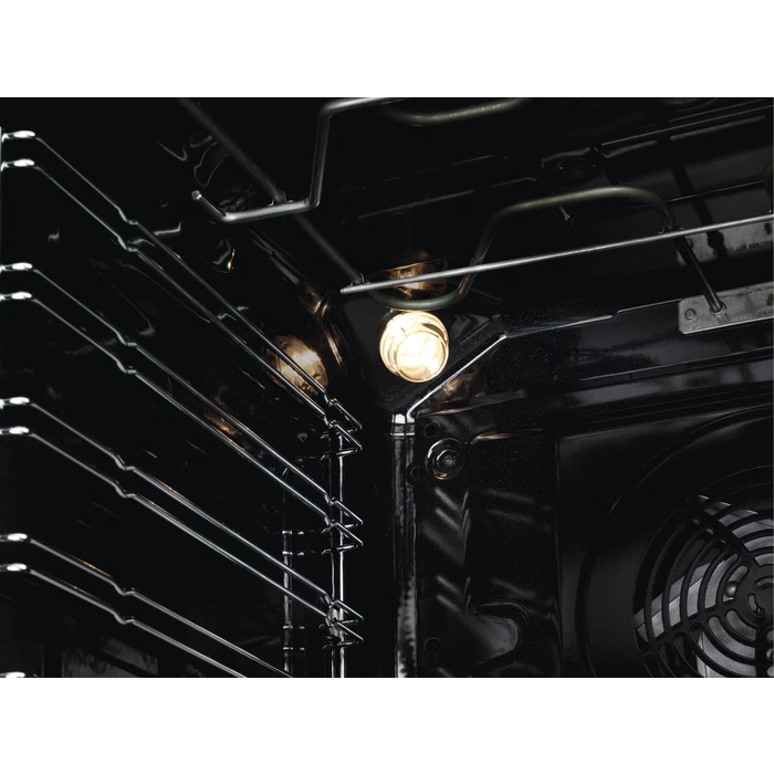 Interior de un horno negro con luz encendida. Se ven rejillas metálicas. El interior es oscuro.