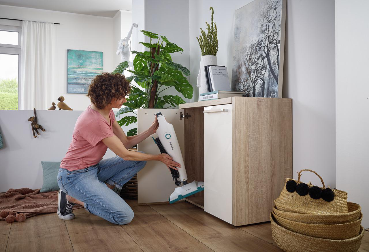 Eine Frau stellt einen Staubsauger in einen Schrank.