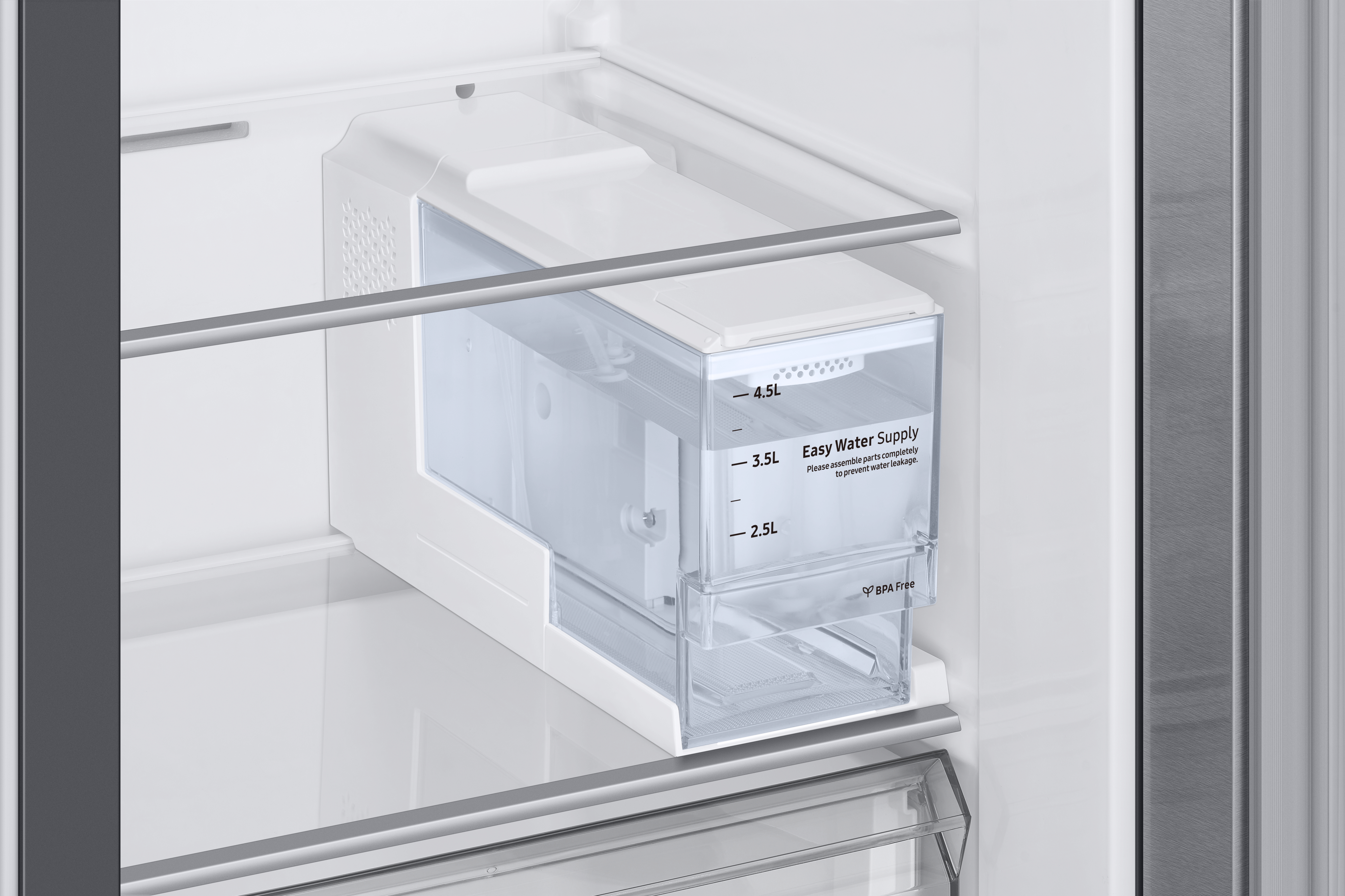 Ein klarer Kunststoff-Wassertank im Kühlschrank. Es ist mit Wasserstandmarkierungen beschriftet.