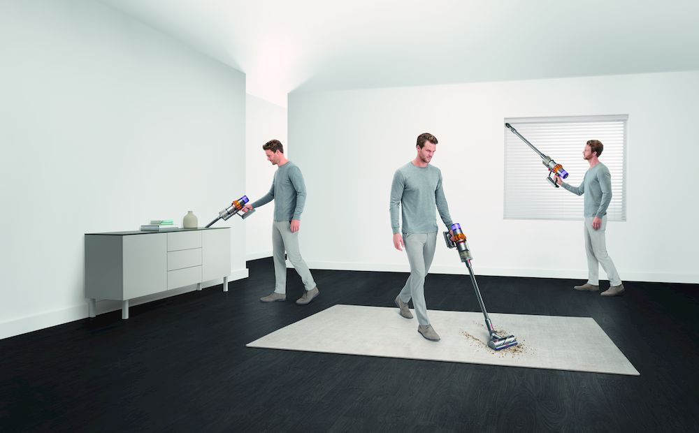 Een man stofzuigt een kamer met een wit tapijt en een zwarte vloer.