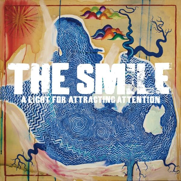 Album borítója a 'THE SMILE' és 'A LIGHT FOR ATTRACTING ATTENTION' szöveggel egy kék művészi dizájn felett.