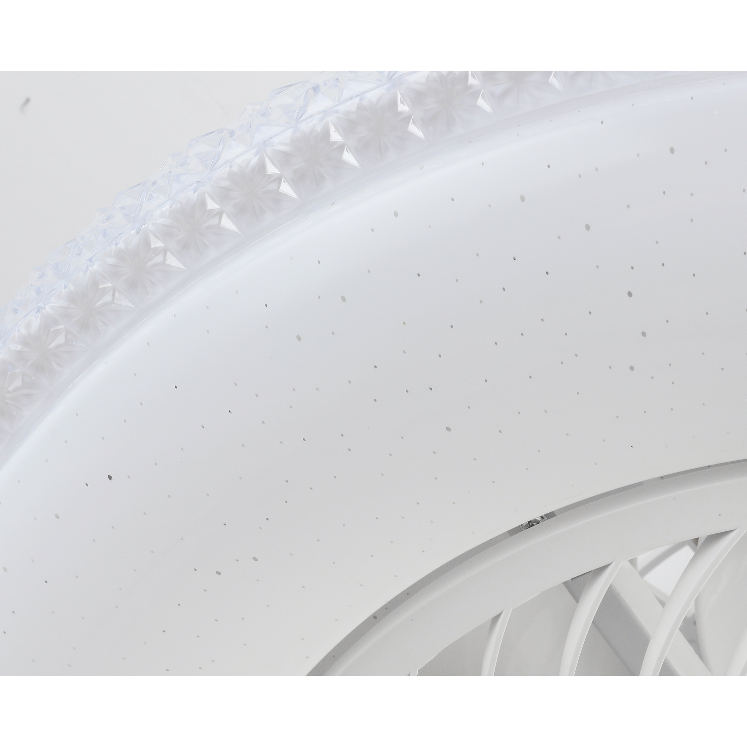 Primer plano de una lámpara de techo blanca y redonda. Tiene un borde decorativo de plástico transparente.