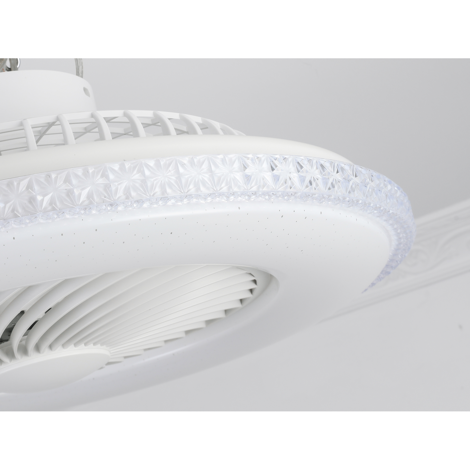 Primer plano de un ventilador de techo blanco con luz decorativa y aspas.