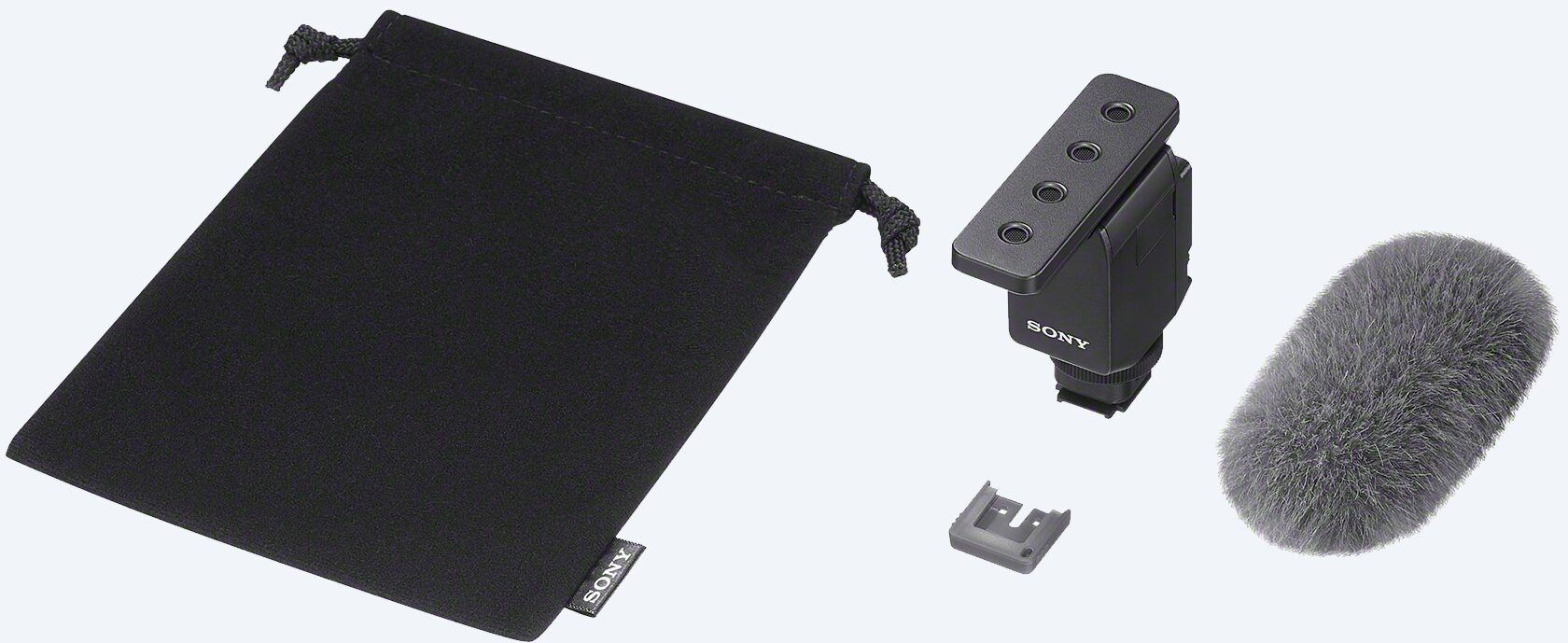 Une pochette noire, un microphone et des accessoires sont disposés sur une surface blanche.
