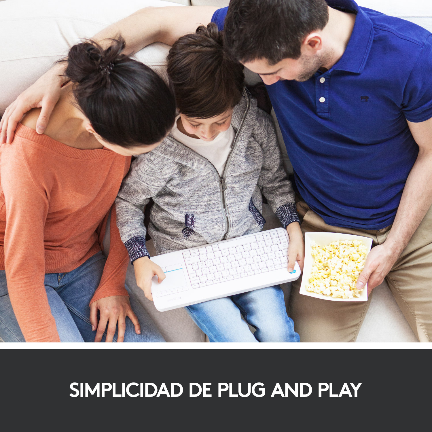 Familia en un sofá, usando un teclado y comiendo palomitas. El texto dice: SIMPLICIDAD DE PLUG AND PLAY.
