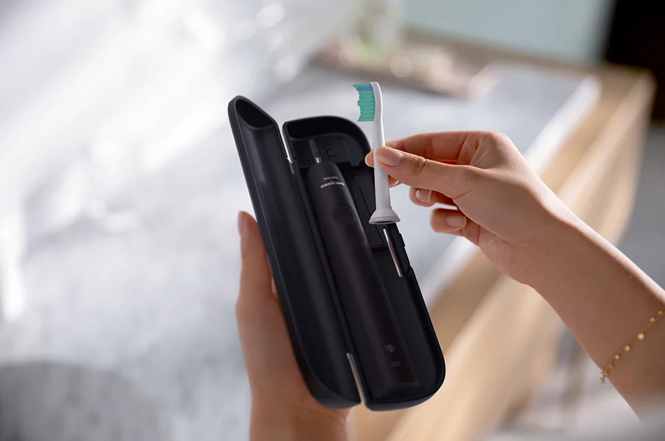 Personne tenant brosse à dents et étui noir, arrière-plan de salle de bain.