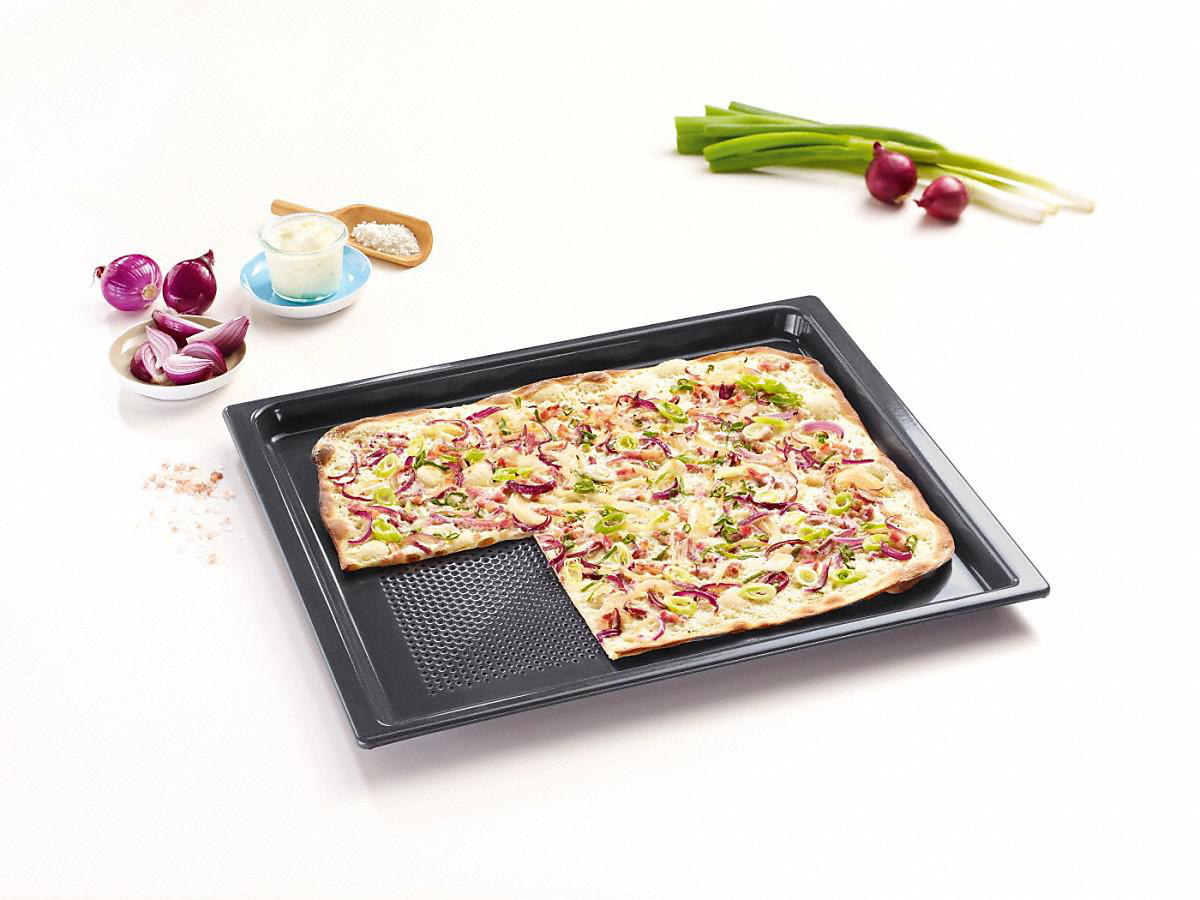 Pizza auf einem schwarzen Tablett. Beläge sind rote Zwiebeln, grüne Zwiebeln und Tomaten.